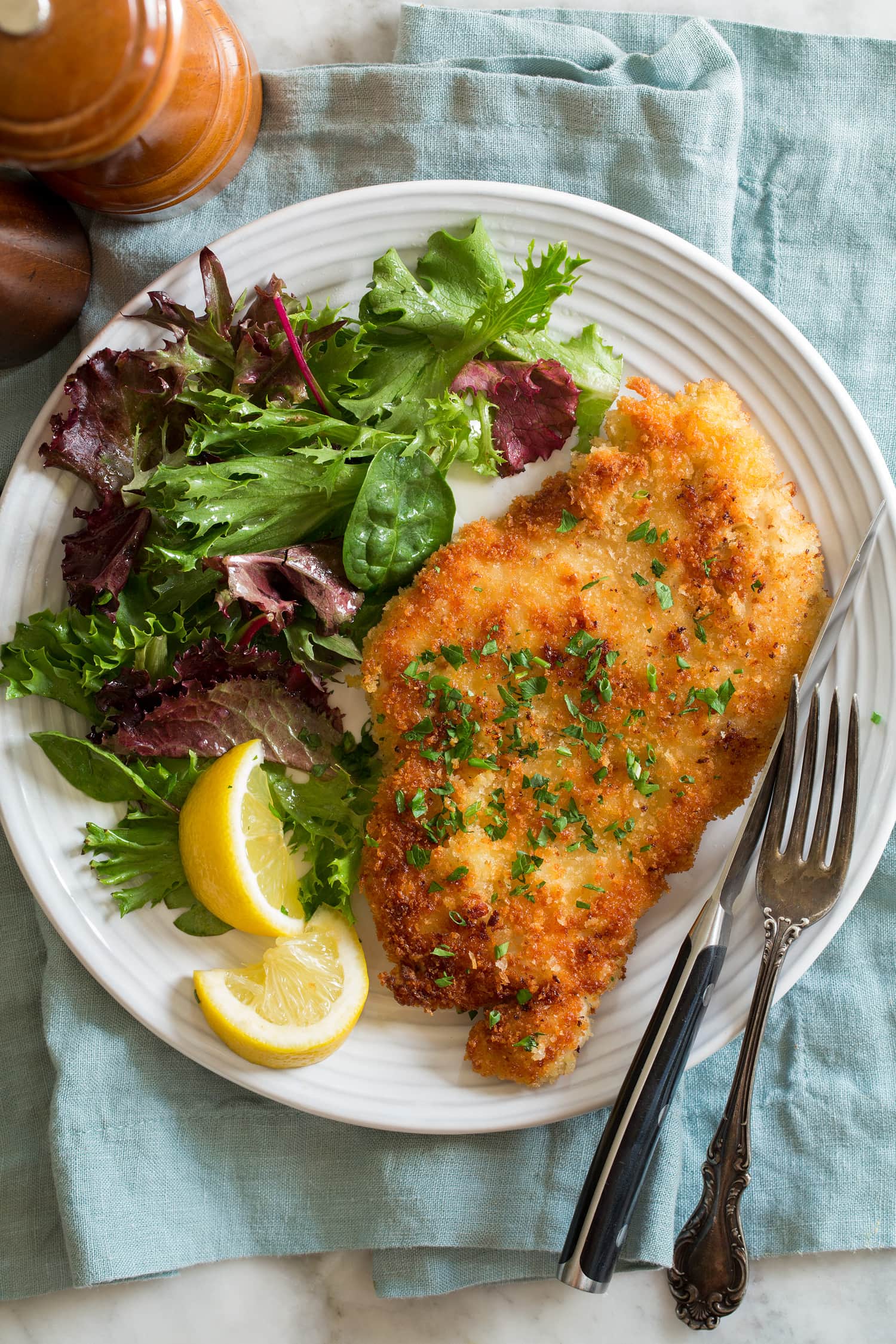 Chicken Schnitzel Chicken schnitzel shown served with lemons and a spring salad.