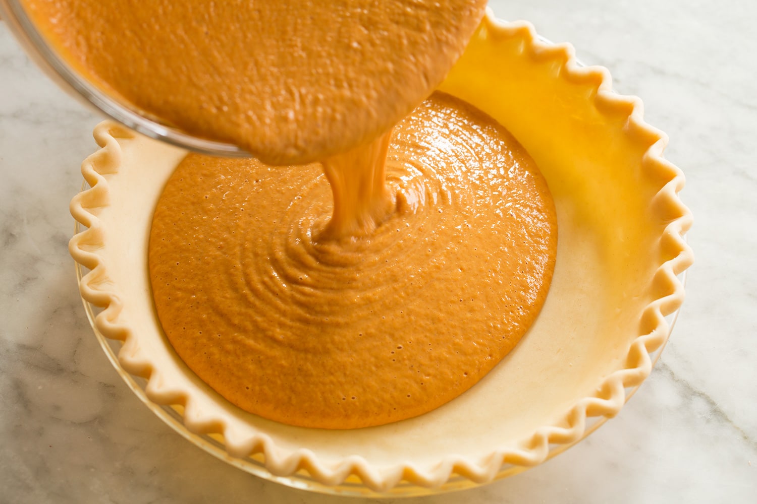 Easy Pumpkin Pie Filling being poured into pie crust.