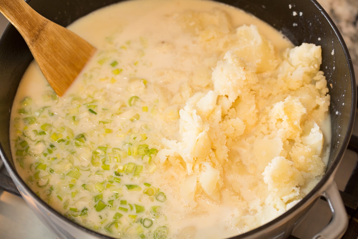 Baked Potato Soup Adding milk and baked potatoes to soup.