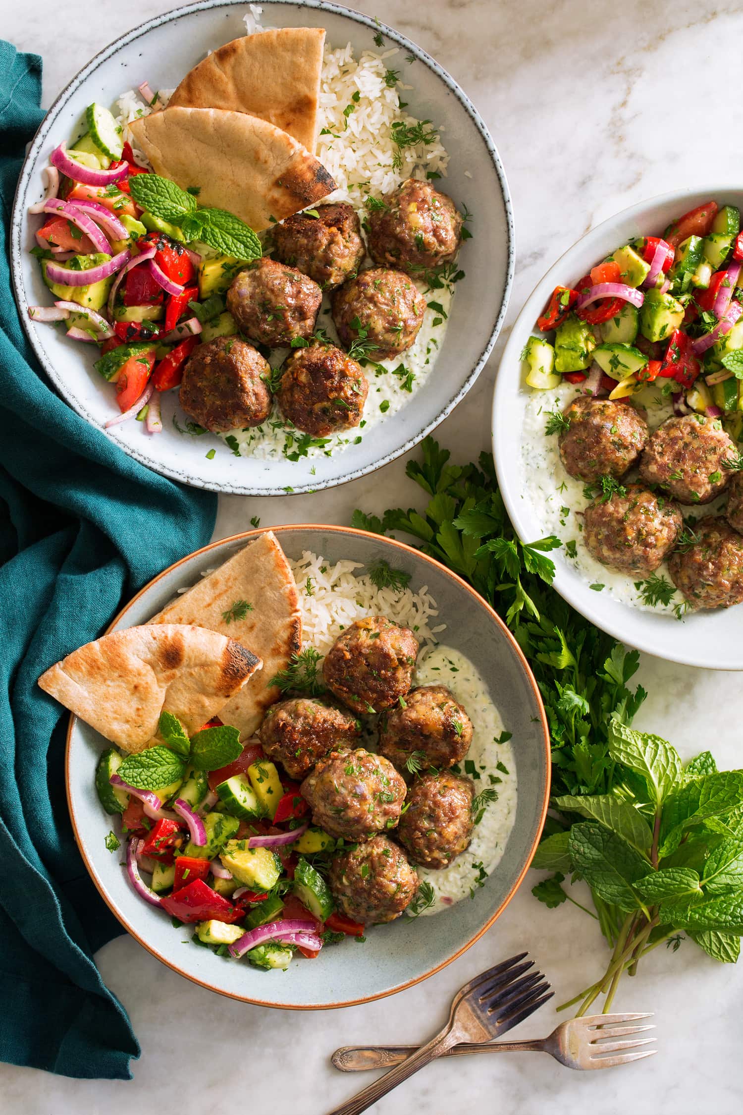Greek Meatballs (Keftedes) Three bowls of greek meatballs with pita and greek salad.