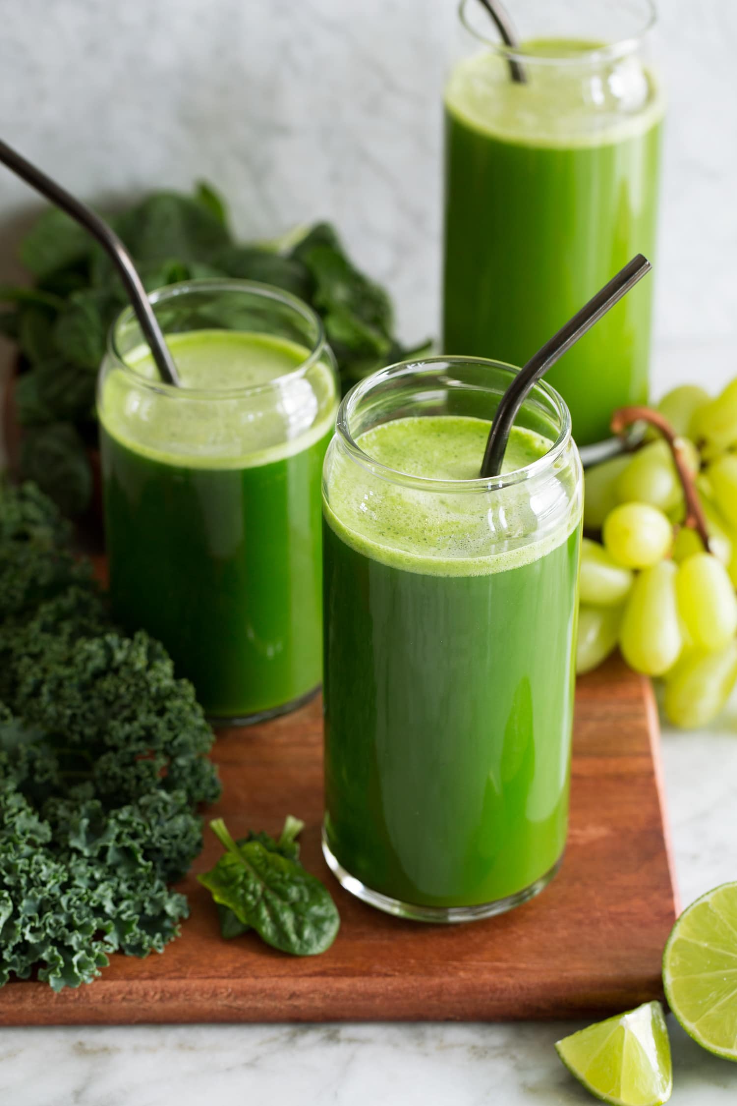 Fresh homemade green juice on a wooden tray over a marble tabletop.
