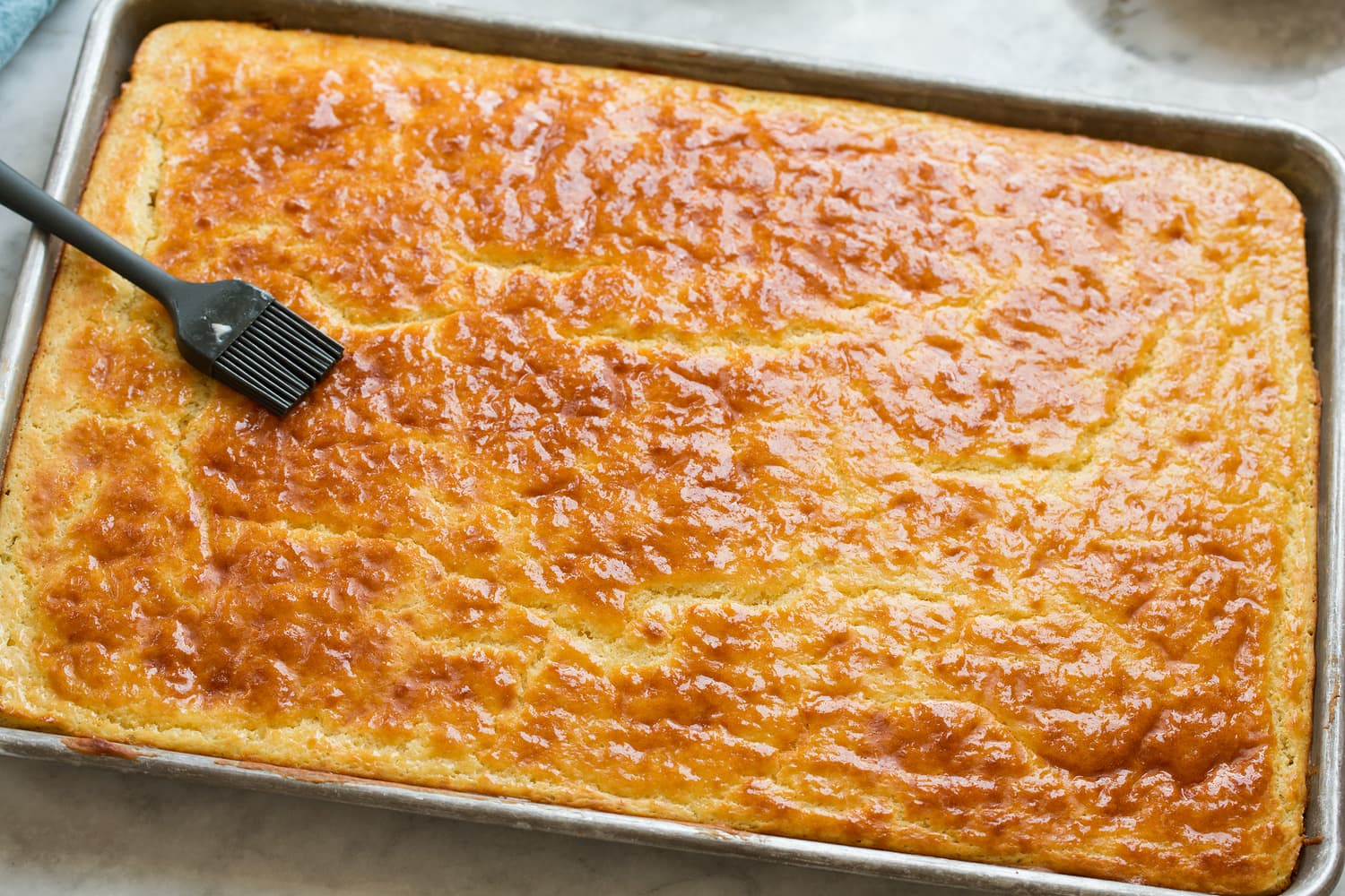 Sheet Pan Pancakes Sheet pan pancake after baking being brushed with melted butter.