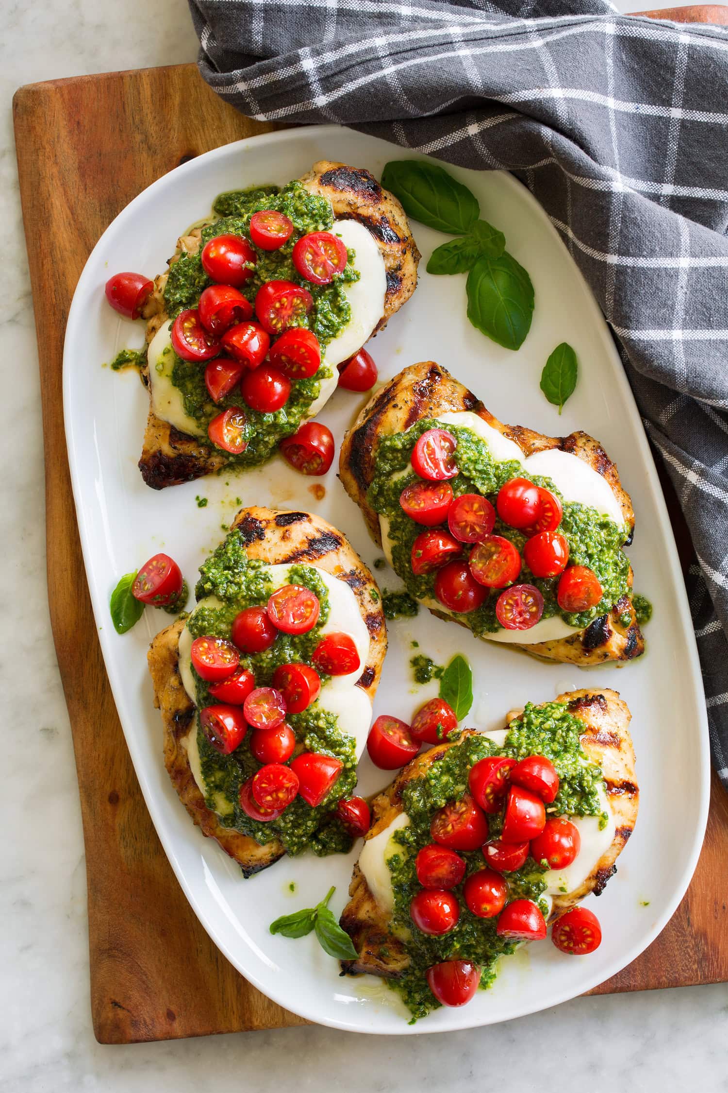 Grilled Chicken Margherita Overhead photo of four pieces of chicken margherita on a white oval serving platter.