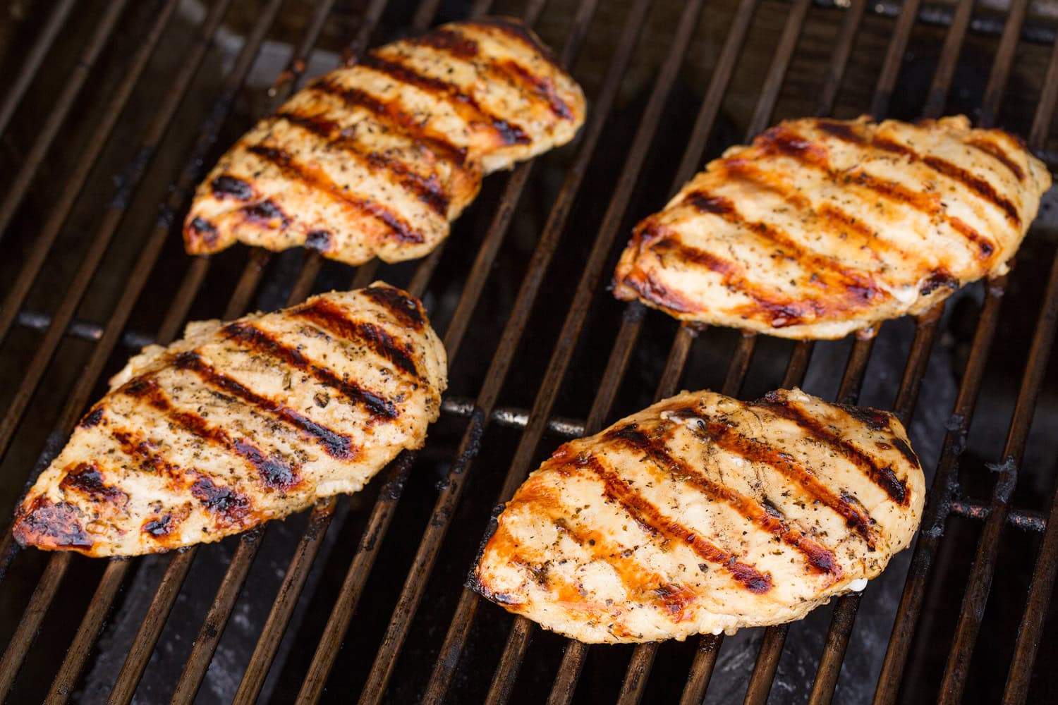 Grilled Chicken Margherita Four chicken breasts on the grill.