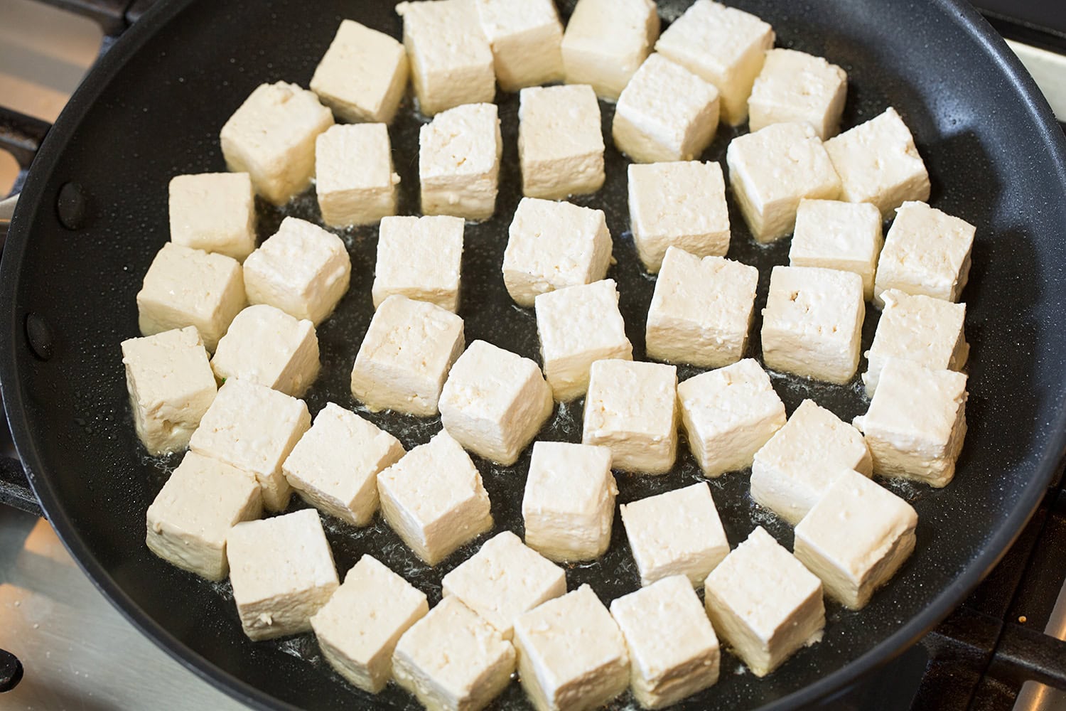 Raw uncooked tofu cubes shown in skillet.