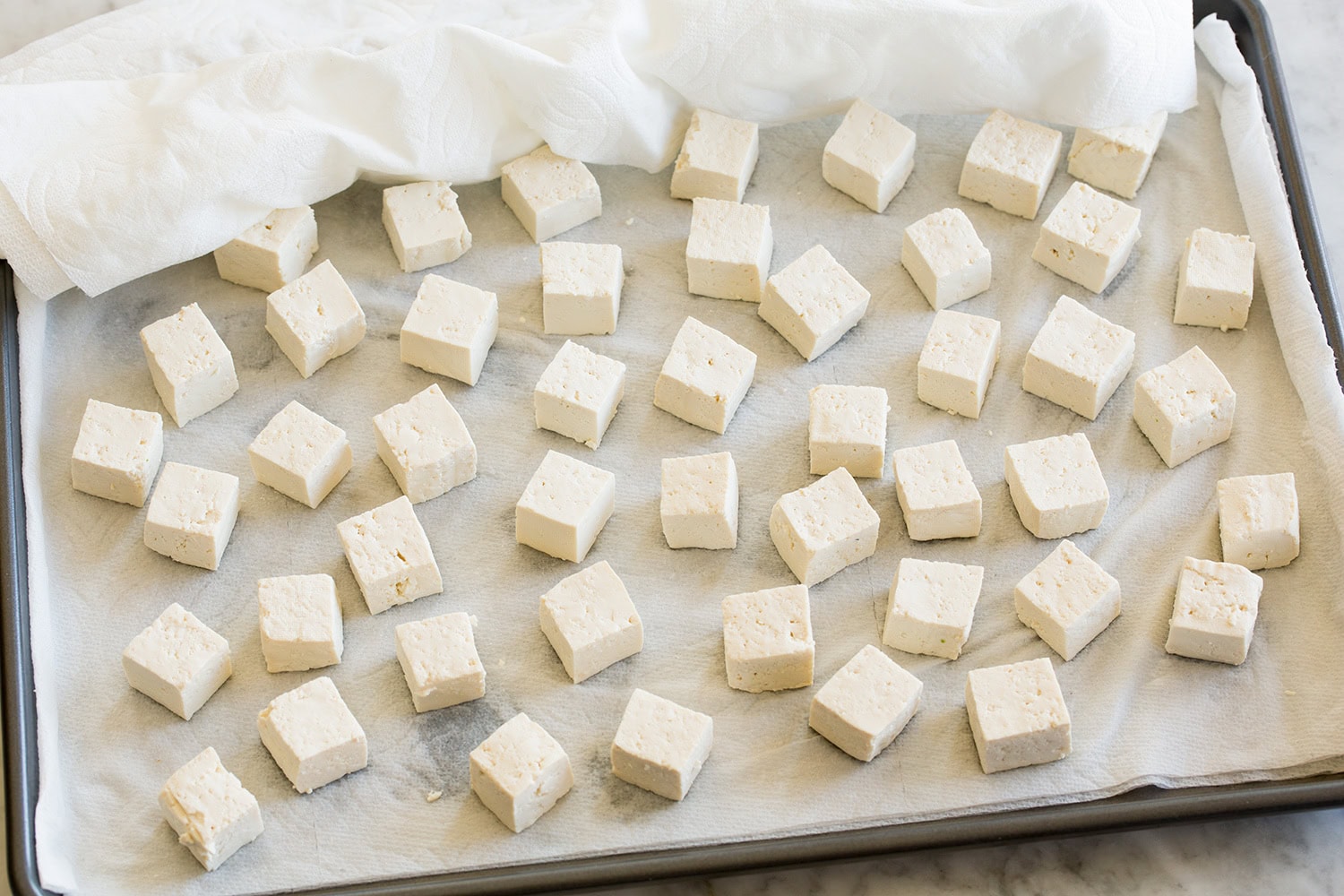 Drying tofu cubes with paper towels.