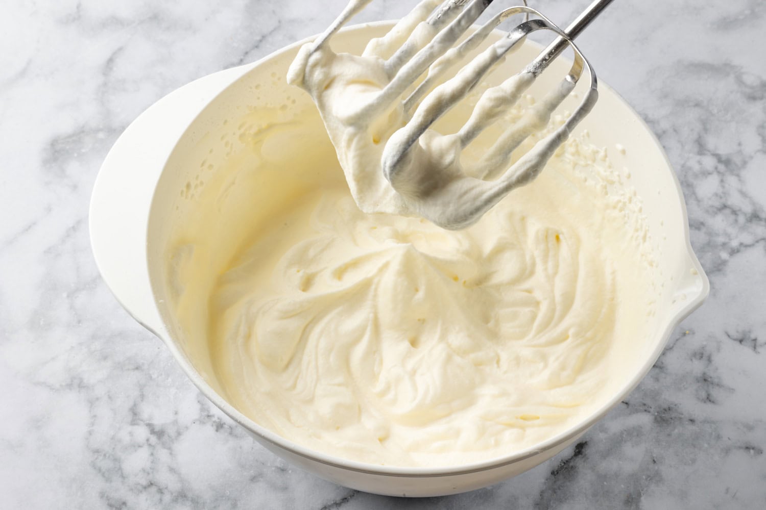 Lemon Icebox Pie Whipped cream in bowl shown with electric beaters.