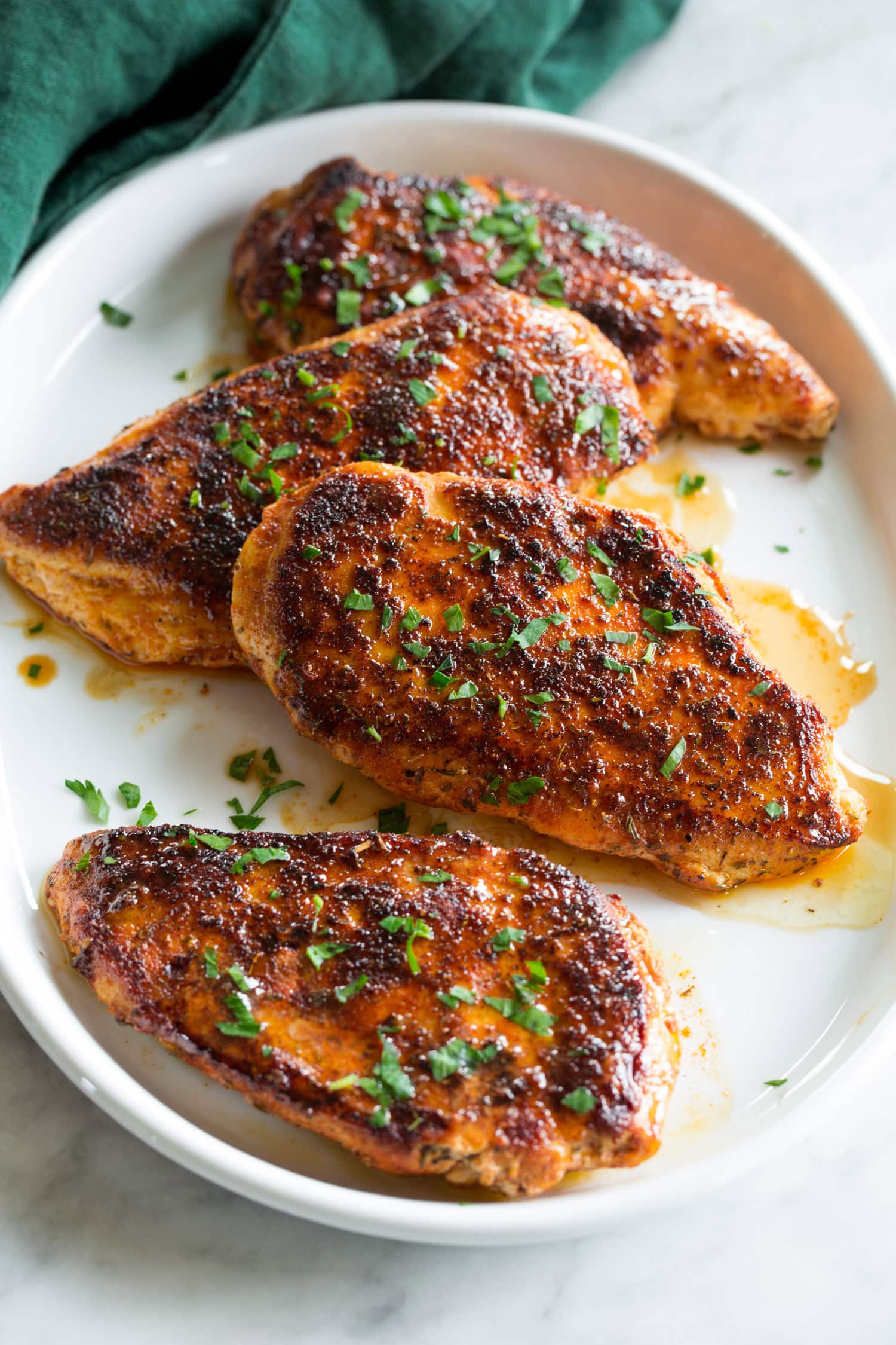 Blackened Chicken Blackened chicken breasts with butter and parsley garnish.