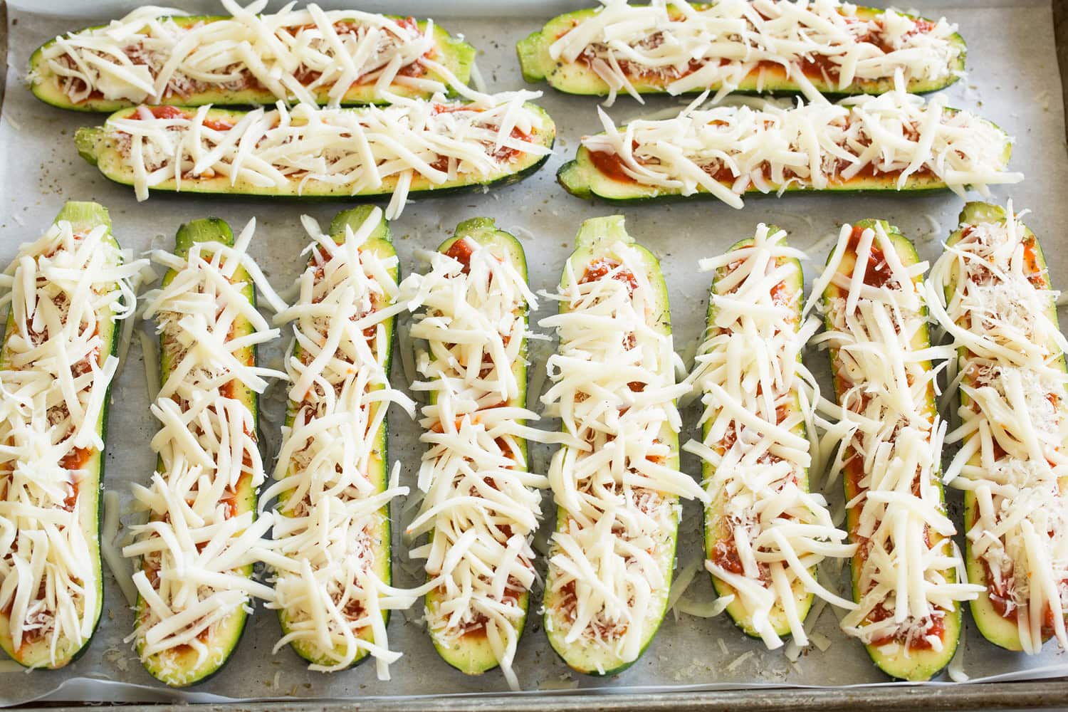 Zucchini Pizza Boats Zucchini pizza boats with shredded cheese on top.