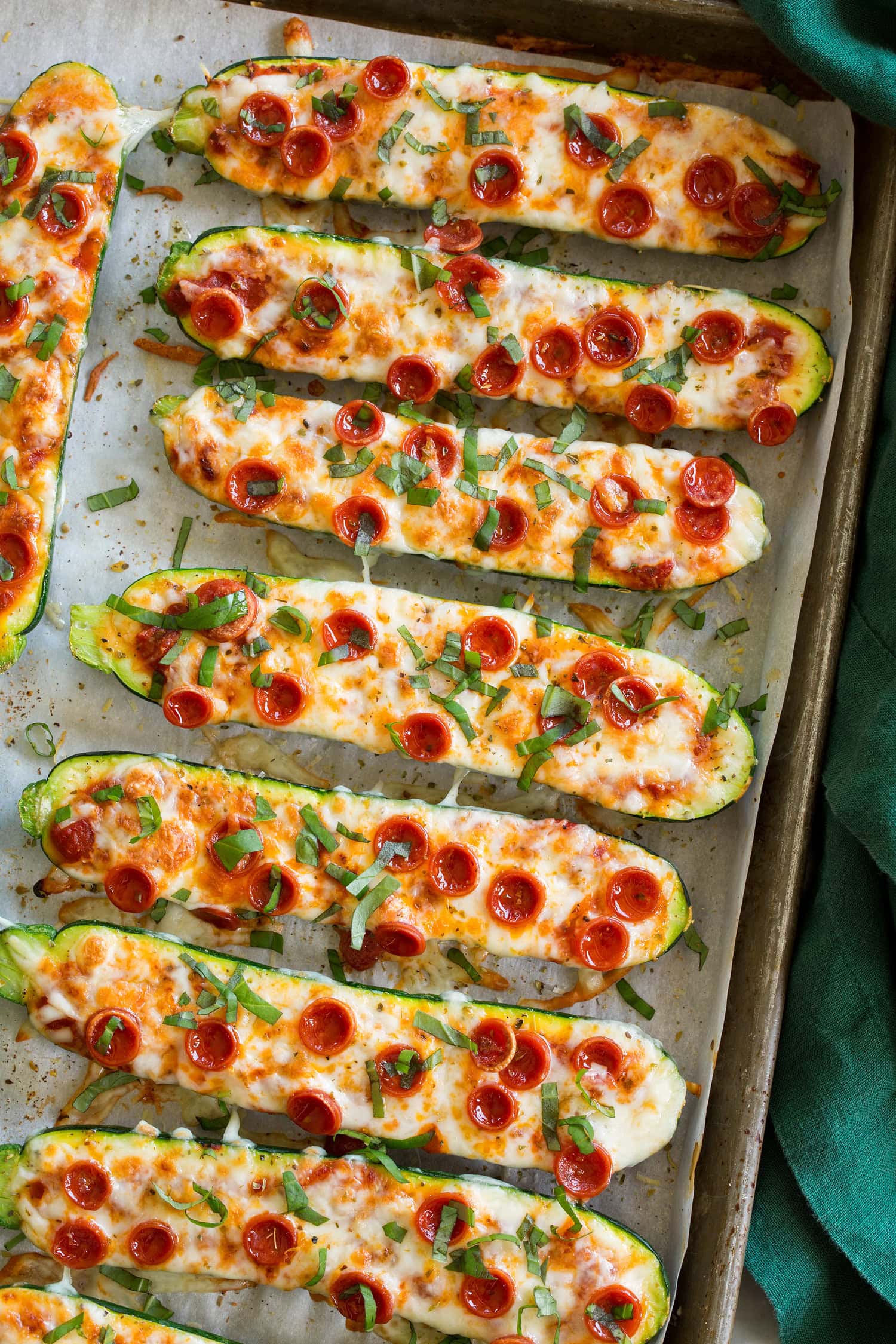 Zucchini Pizza Boats Zucchini halves with melted mozzarella, pizza sauce, pepperoni, and basil on top.