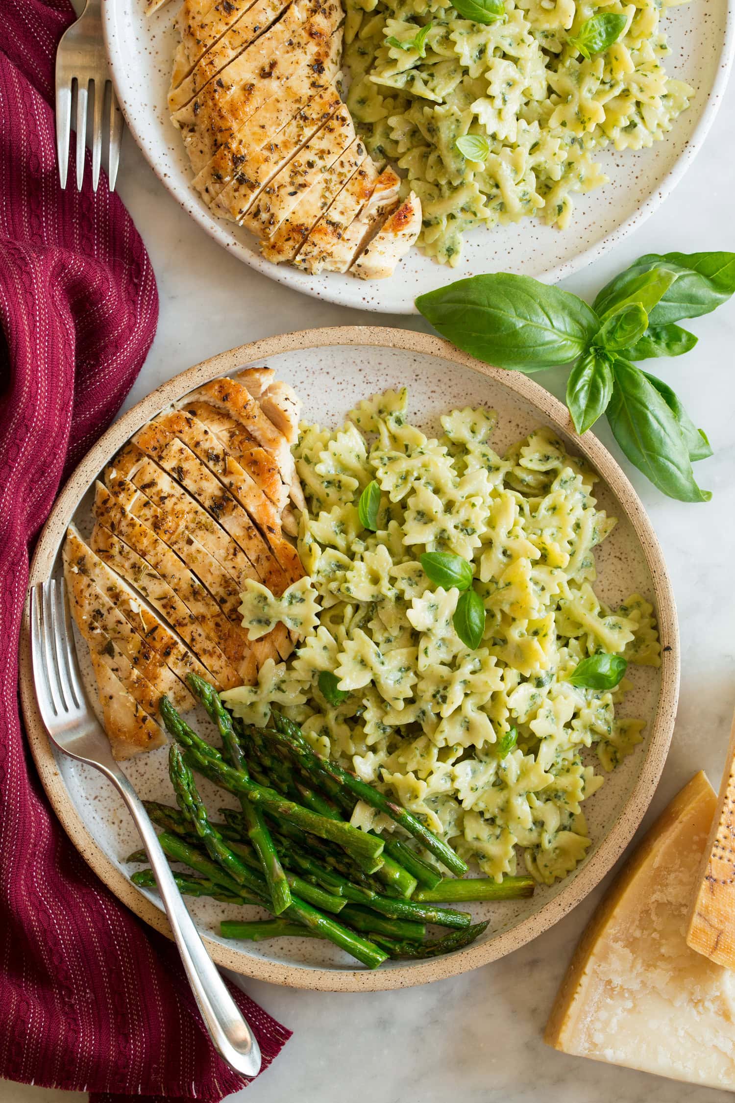 Creamy Pesto Pasta Creamy pesto pasta served with seared chicken breasts and asparagus as a serving suggestion.