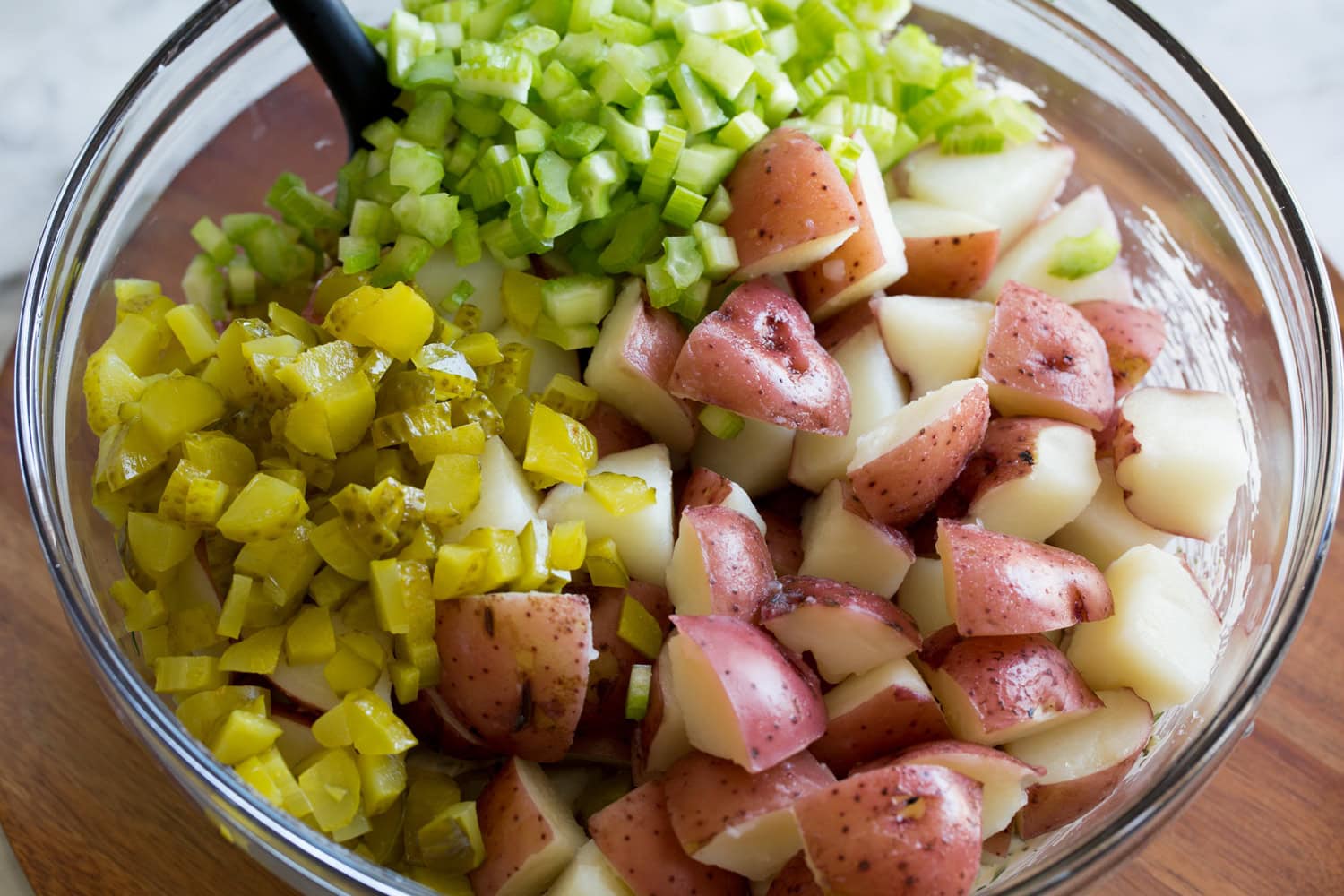 Red Potato Salad Potatoes, celery and pickles added to mixing bowl with dressing.