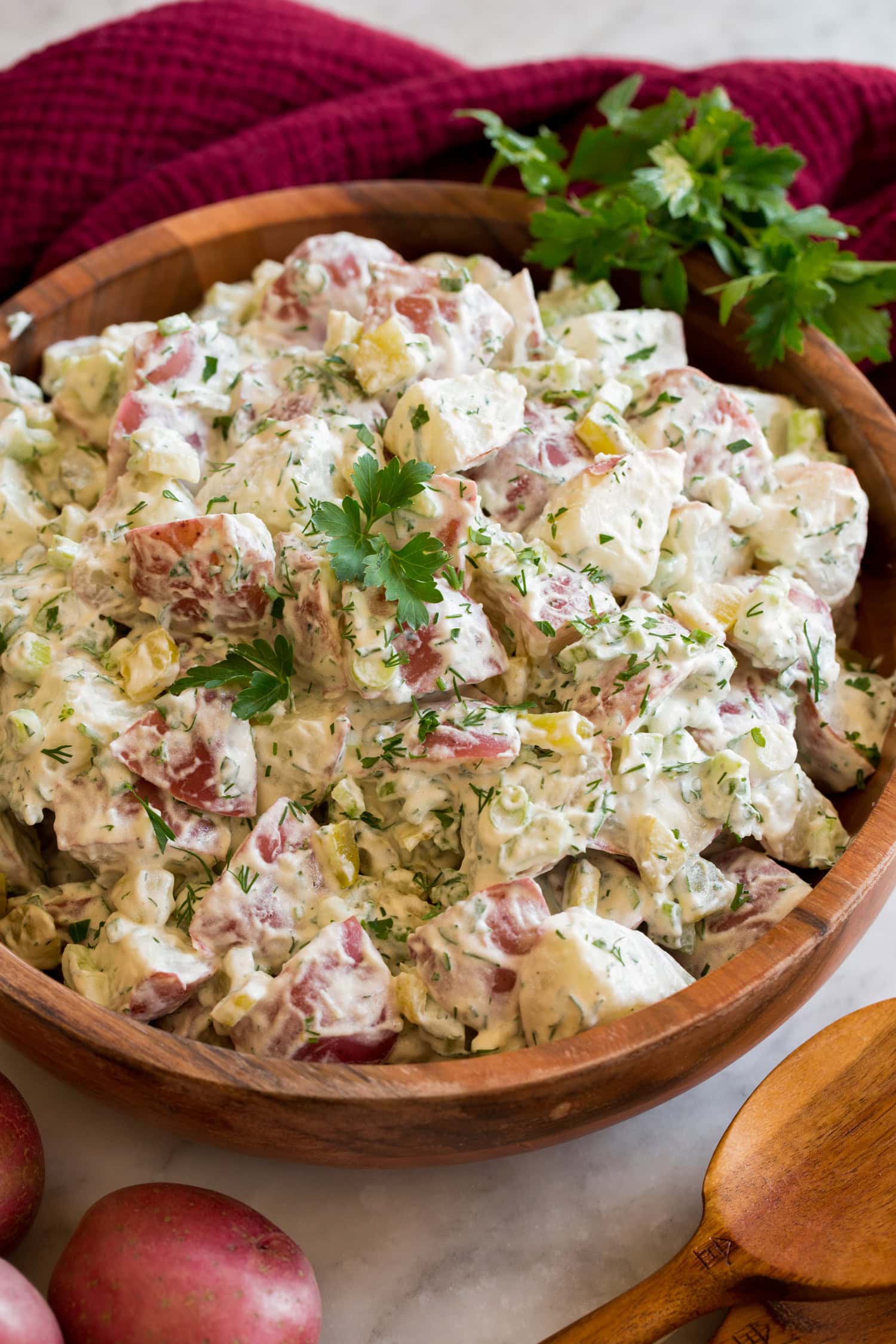 Red Potato Salad Red Potato Salad in a wooden bowl shown garnished with fresh parsley and dill.