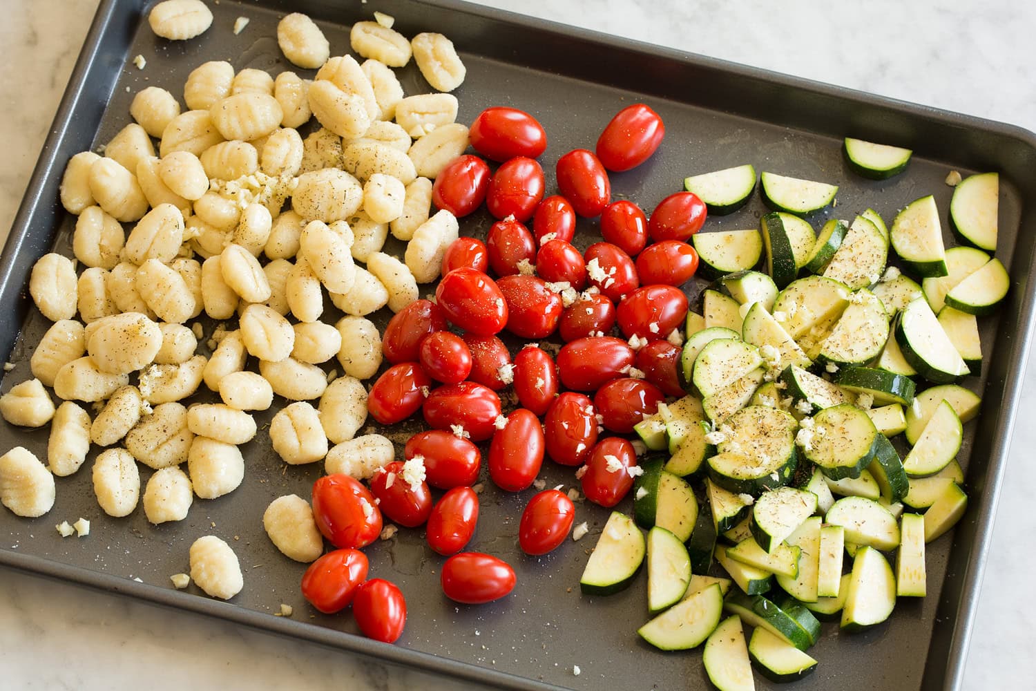 Sheet Pan Gnocchi with Zucchini and Tomatoes Gnocchi, tomatoes and zucchini on a baking sheet before tossing.
