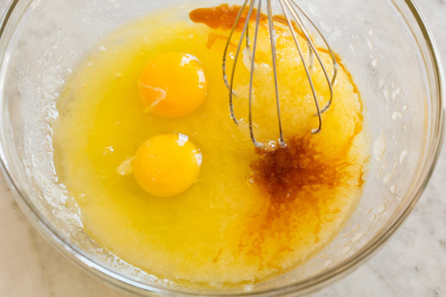 Brownie Bites Eggs and vanilla with melted butter mixture in mixing bowl.