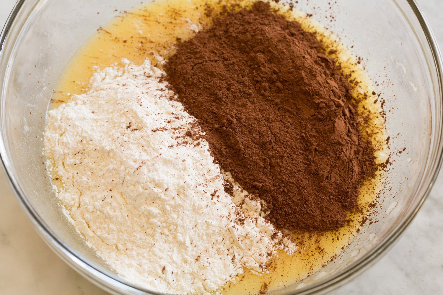 Brownie Bites Cocoa and flour added to butter mixture in mixing bowl.