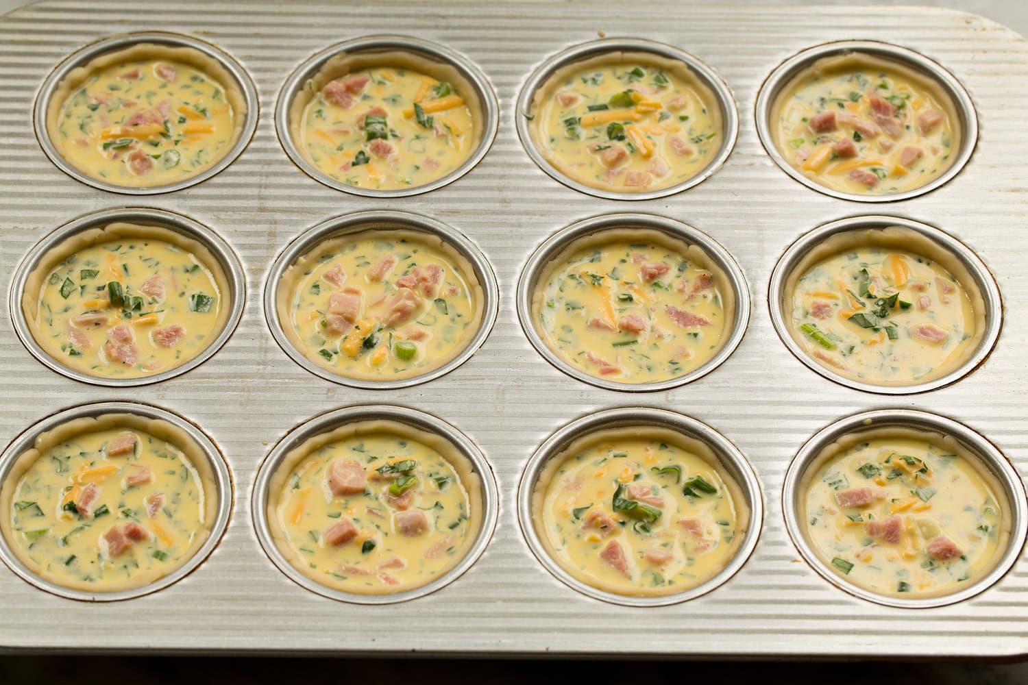 Mini Quiche Filled pie crusts in muffin pan.