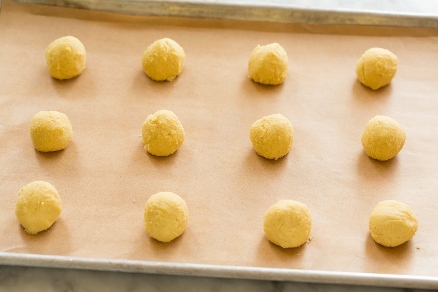 Lemon Cookies Rolled lemon cookie dough balls on baking sheet.