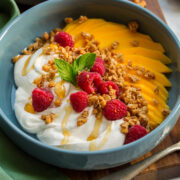 Whipped yogurt shown with honey drizzled over, fruit and granola on the side.