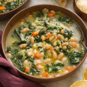 Serving of white bean and kale soup in a brown bowl.