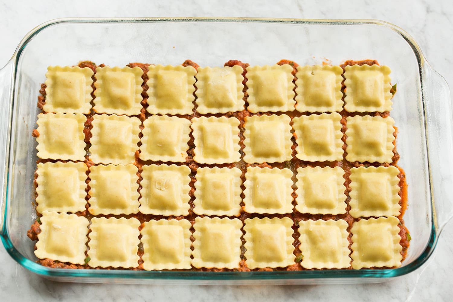 First layer of ravioli layered in a baking dish.