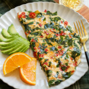 Healthy egg white omelette served with avocado slices and sliced oranges.