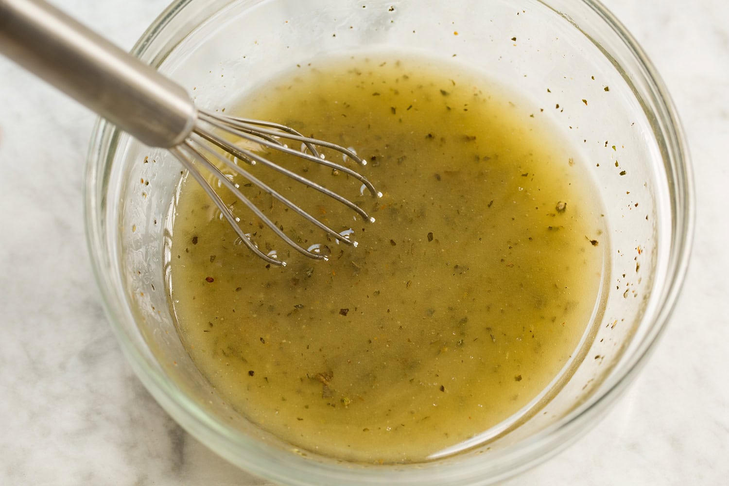 Tortellini Pasta Salad Dressing for pasta salad being mixed together in a glass dish.