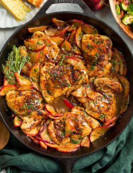 Apple Chicken in a cast iron pan shown from overhead sitting on a green cloth.