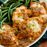 French onion chicken served on a white platter with green beans.