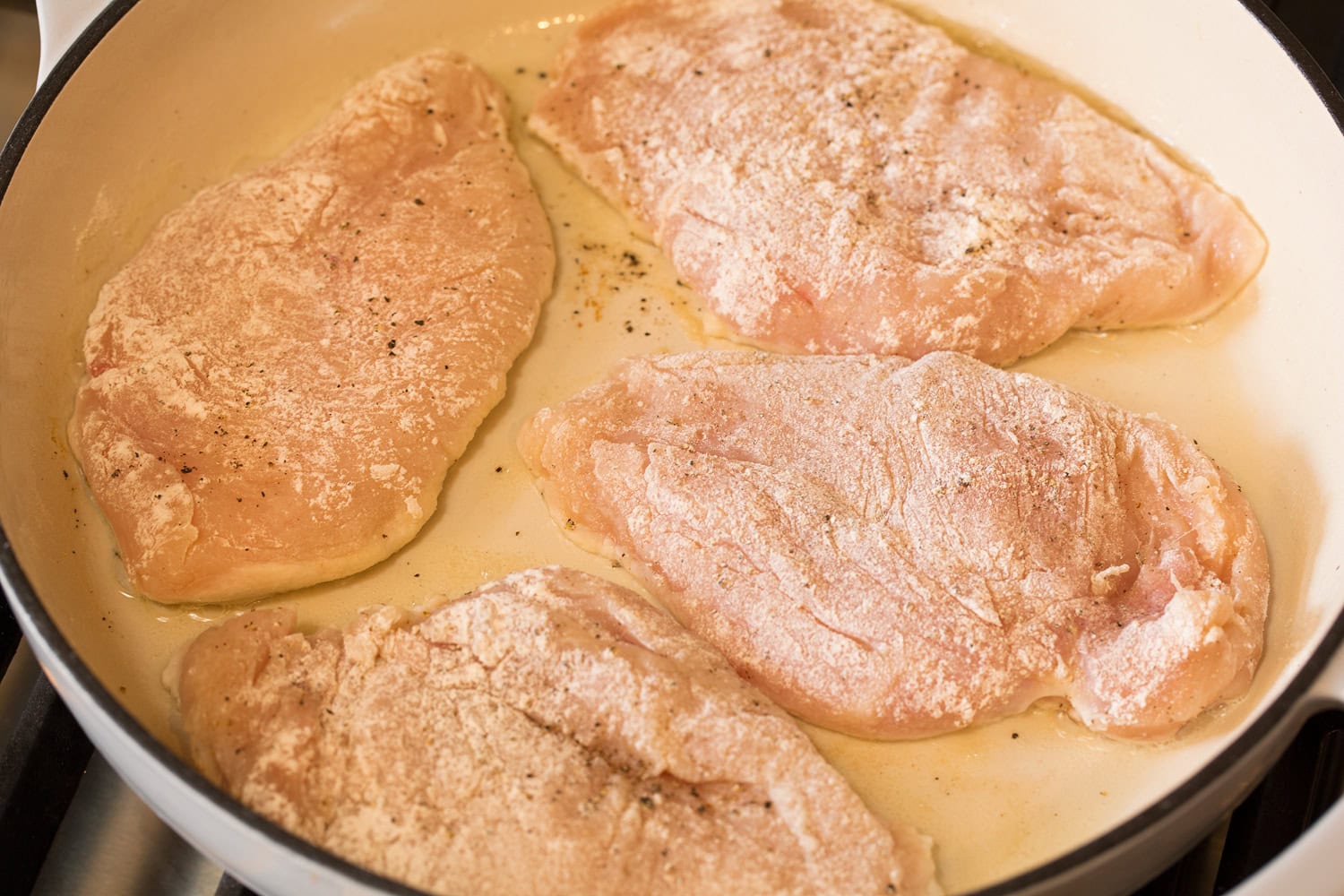 French Onion Chicken Flour coated chicken breasts shown raw in skillet before cooking.