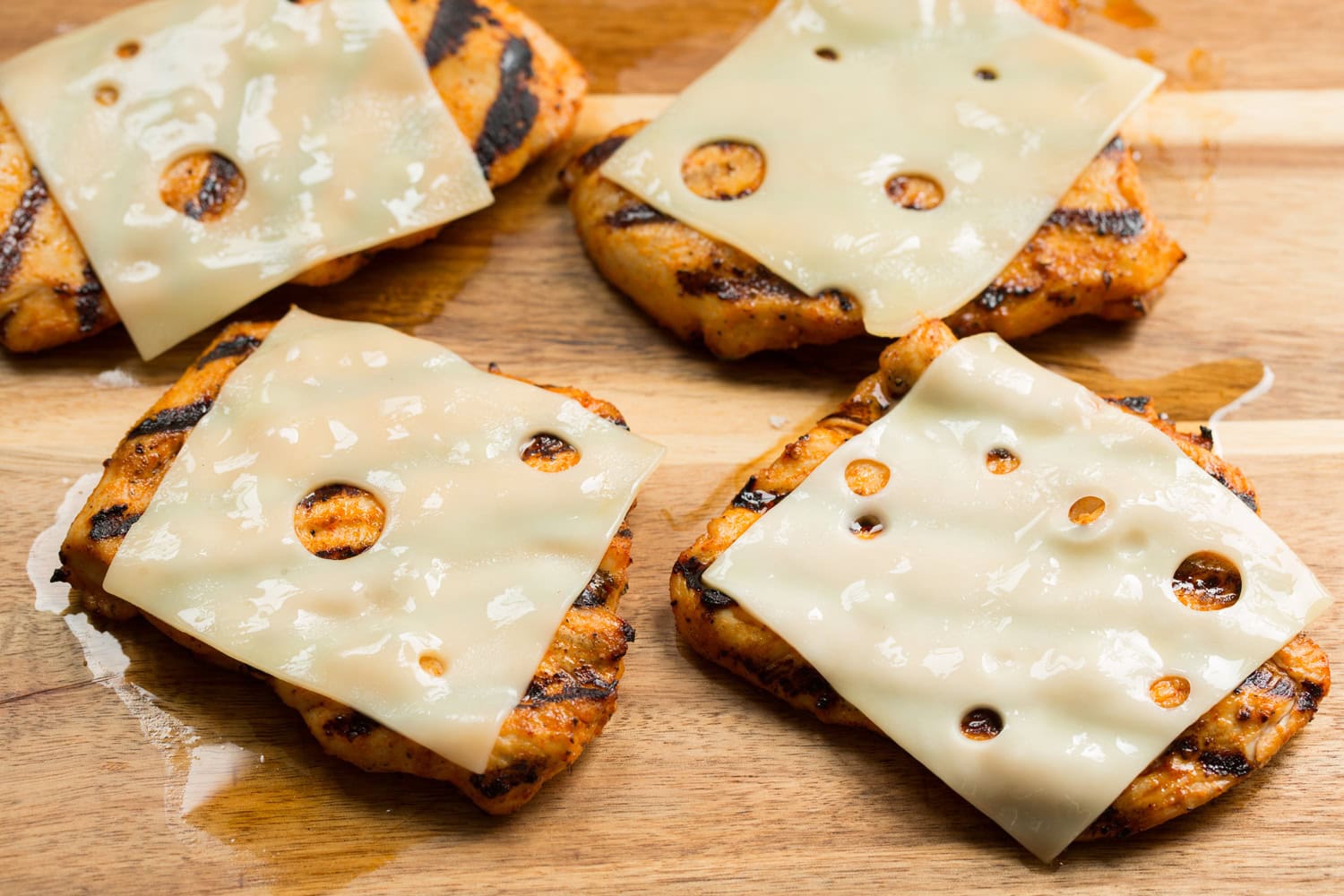 Grilled chicken portions with cheese slices melted on top. Grilled chicken portions with cheese slices melted on top.