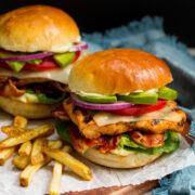 Grilled Chicken Sandwich layered with grilled chicken breast, lettuce, bacon, cheese, tomato, avocado, ranch mayo and buns.