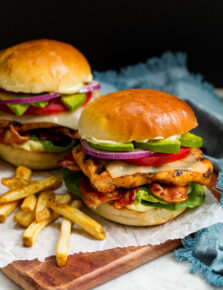 Grilled Chicken Sandwich layered with grilled chicken breast, lettuce, bacon, cheese, tomato, avocado, ranch mayo and buns.