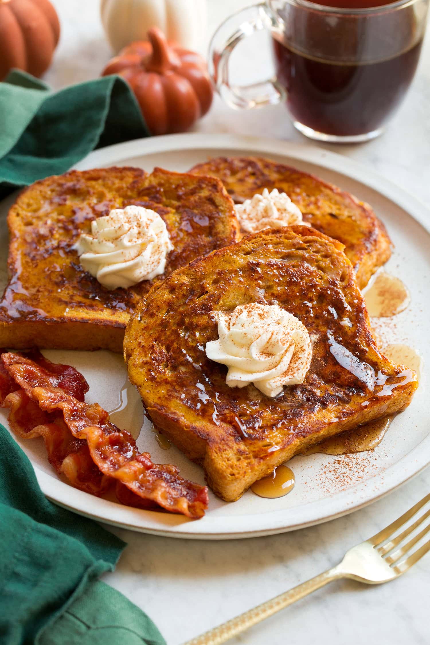 Pumpkin French Toast Three slices of homemade pumpkin french toast with maple syrup and whipped cream swirled on top.