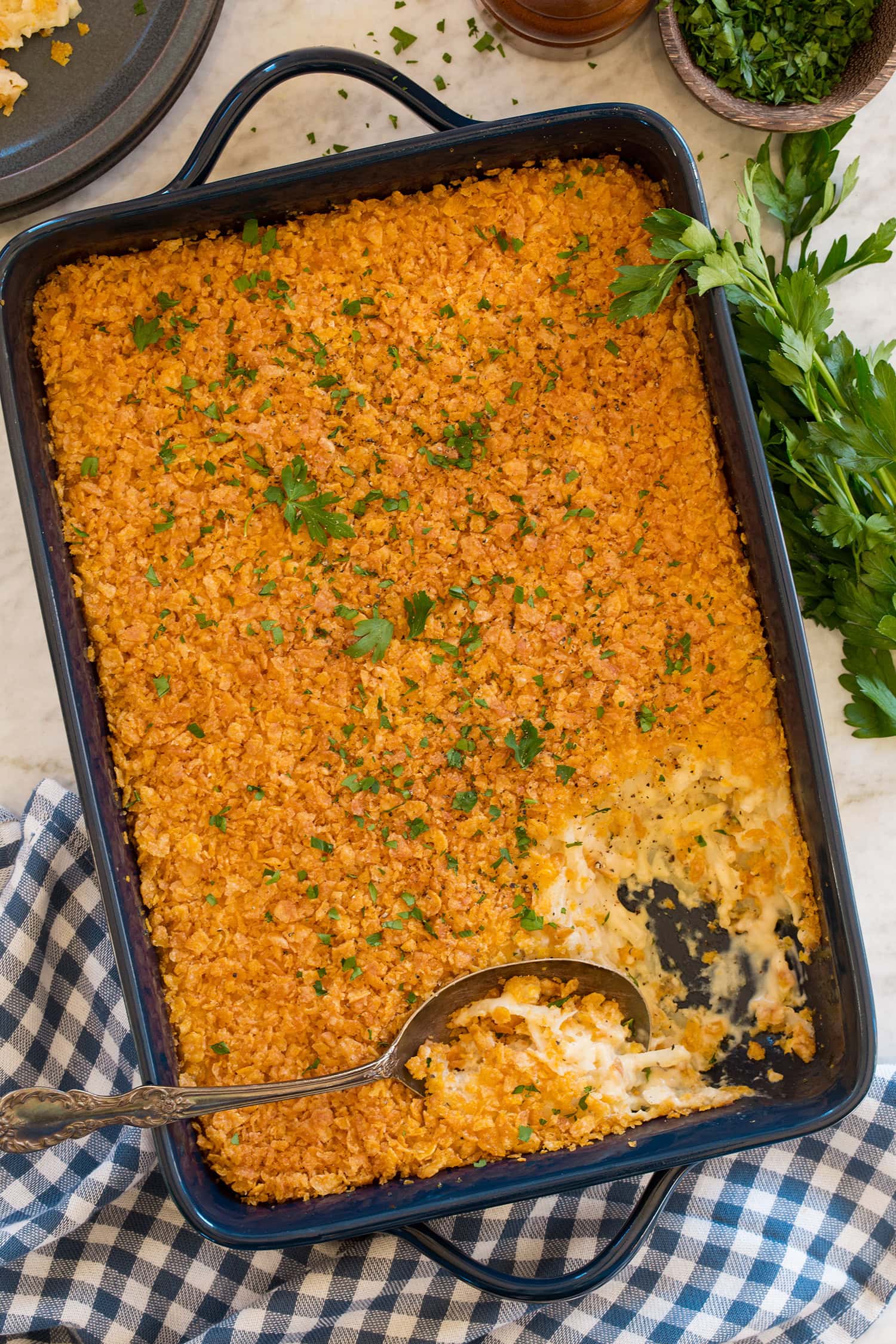 Funeral Potatoes Funeral potato casserole in a navy baking dish with a scoopful removed to show interior.