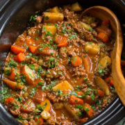 Ground beef stew with potatoes and carrots in a slow cooker.