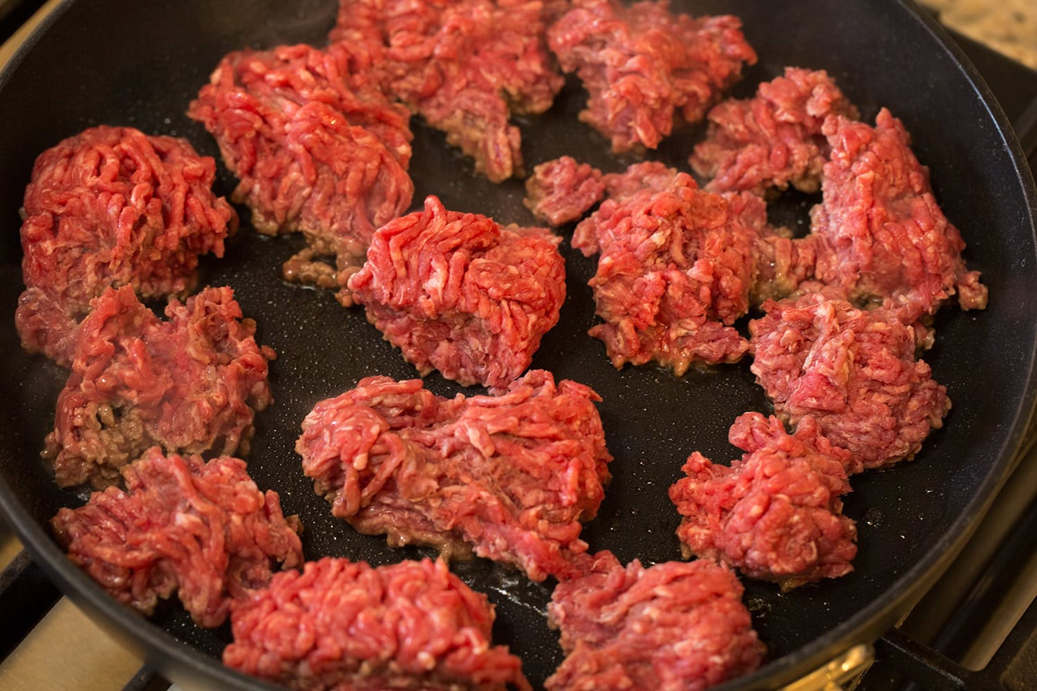 Slow Cooker Ground Beef Stew Searing ground beef in chunks in a skillet.