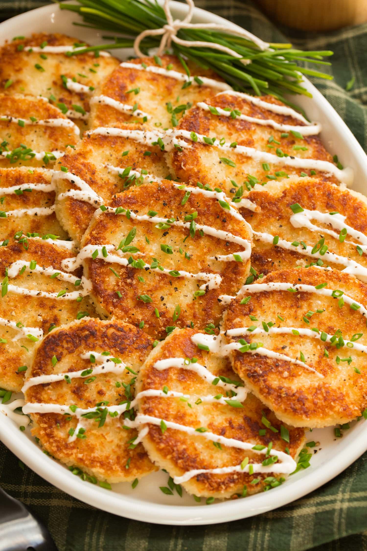 Mashed Potato Cakes Mashed potato cakes covered with panko, drizzled with sour cream and garnished with chives.