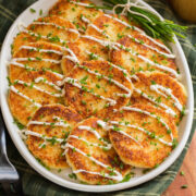 Potato cakes on a white oval platter over a green gingham cloth.