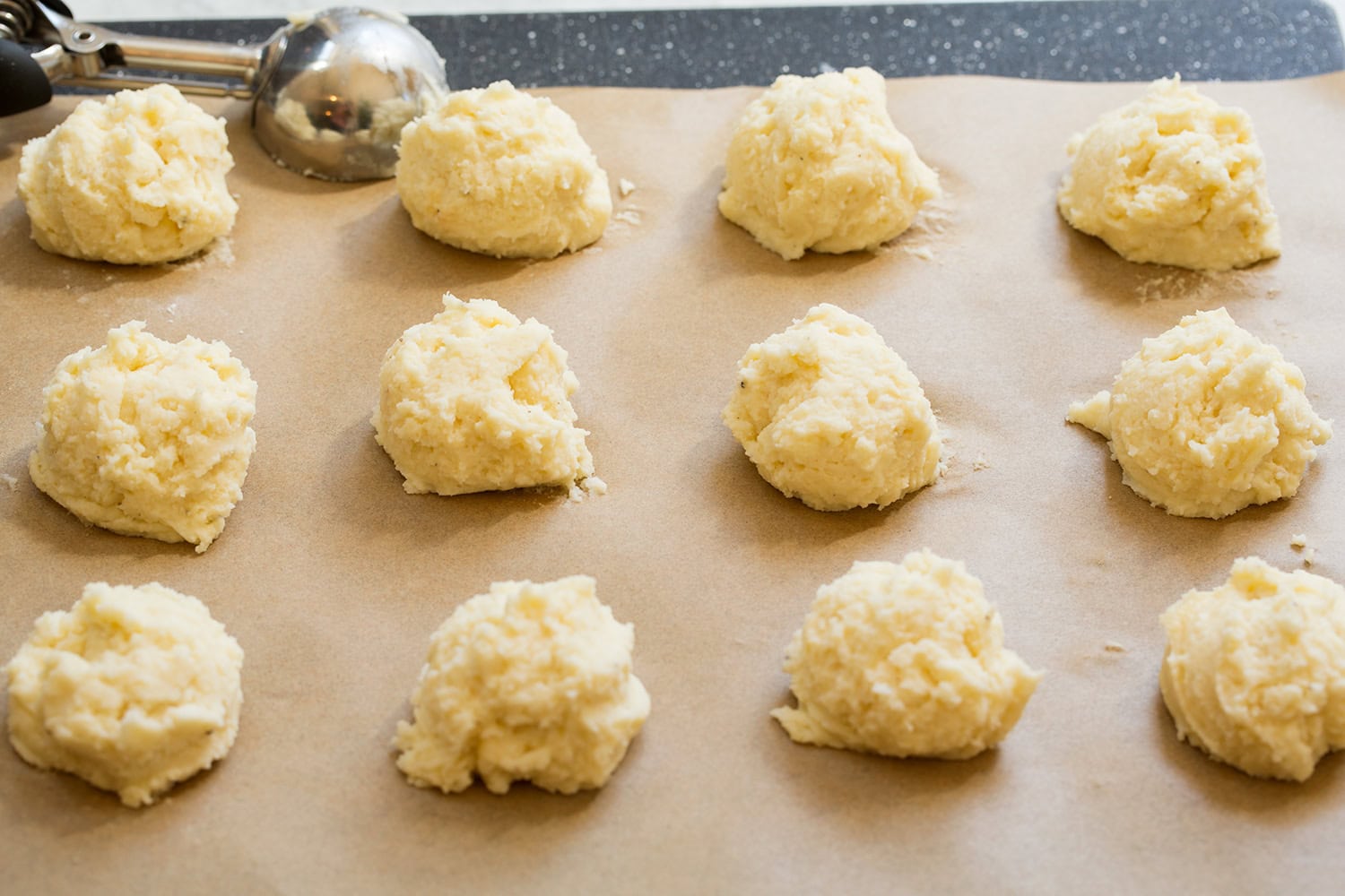 Mashed Potato Cakes Scoopfuls of mashed potato cake mixture on parchment paper.