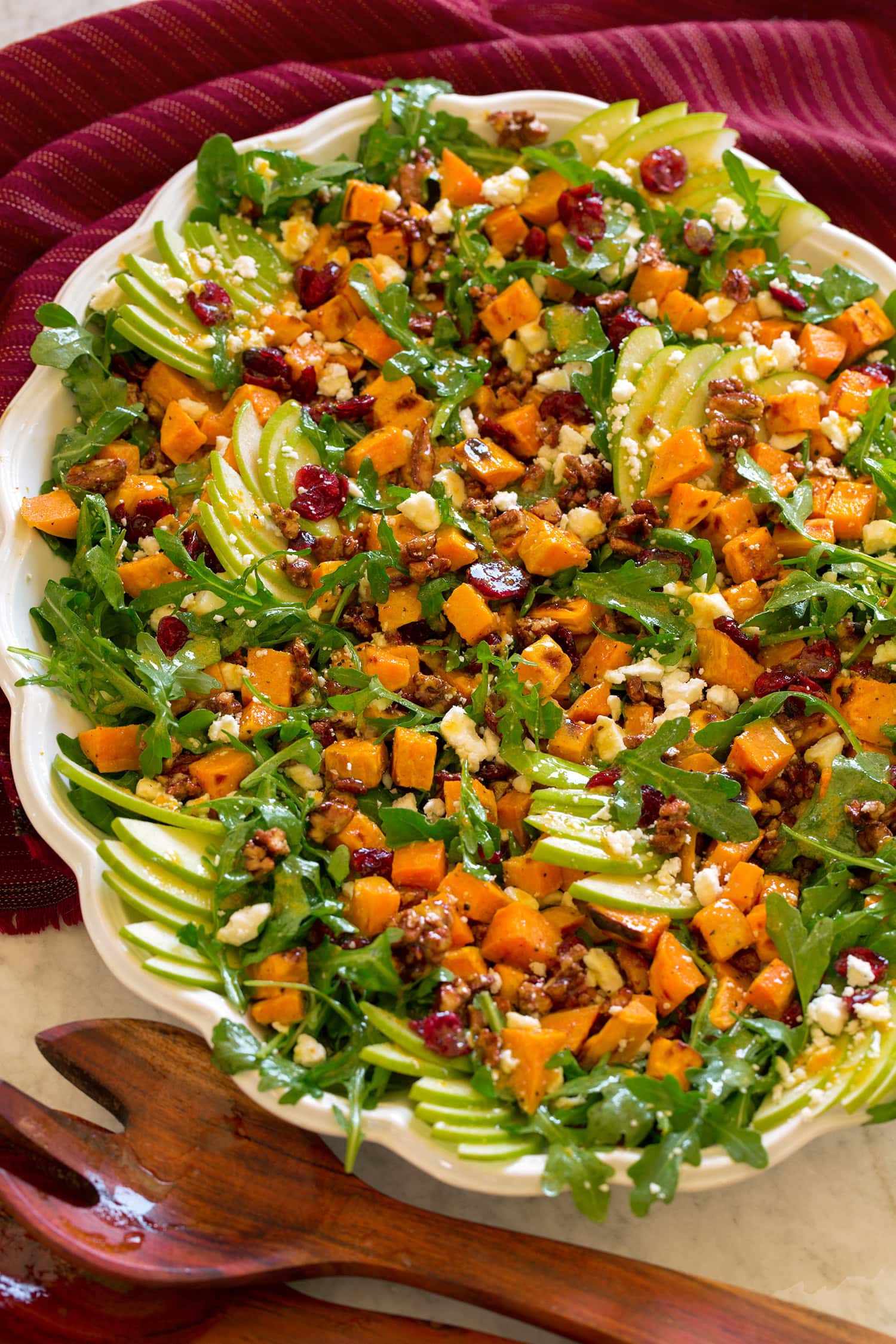 Sweet Potato Salad Sweet potato salad shown from a side angle on a white oval platter with wooden tongs to the side.
