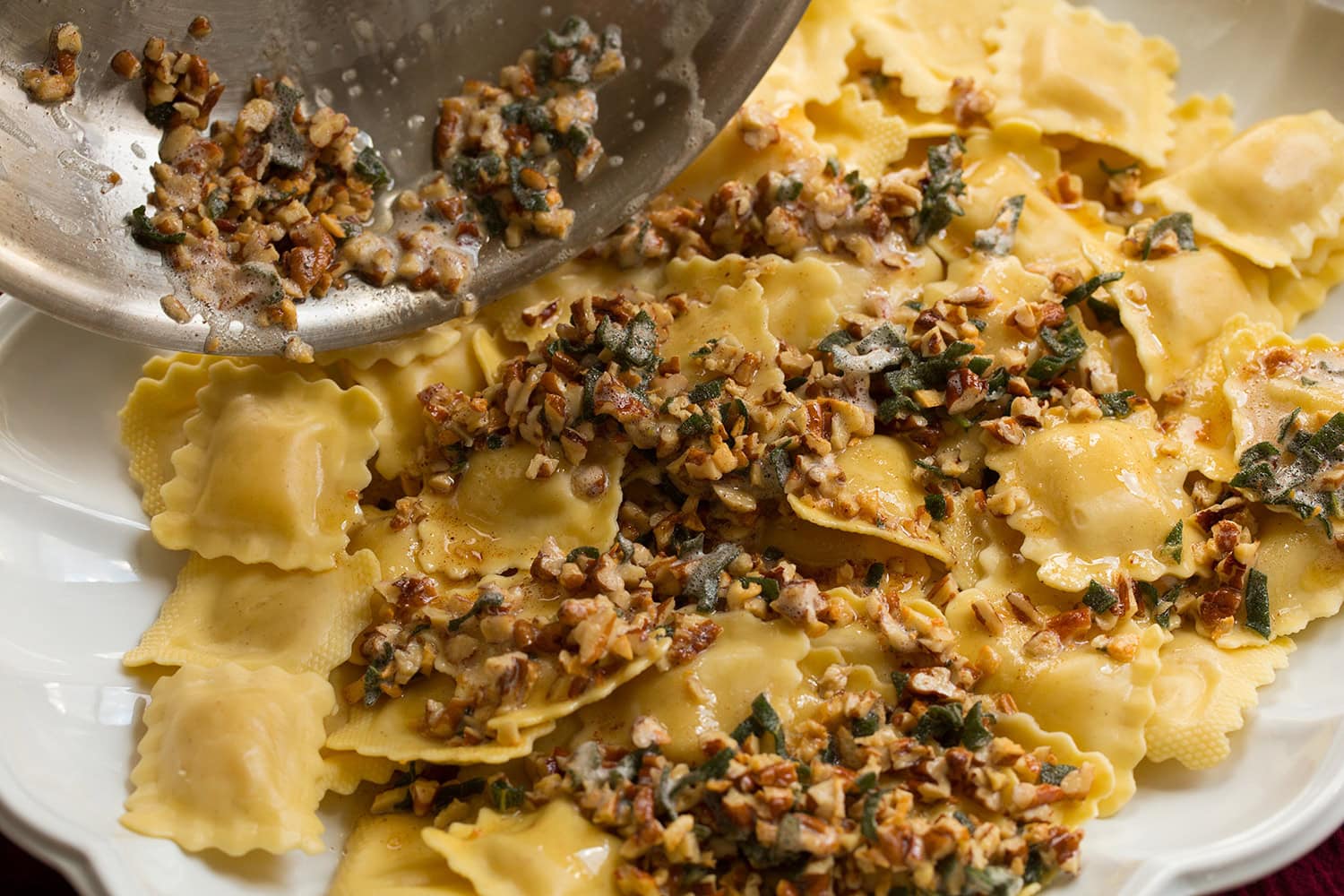 Browned butter sage sauce being poured over pasta.
