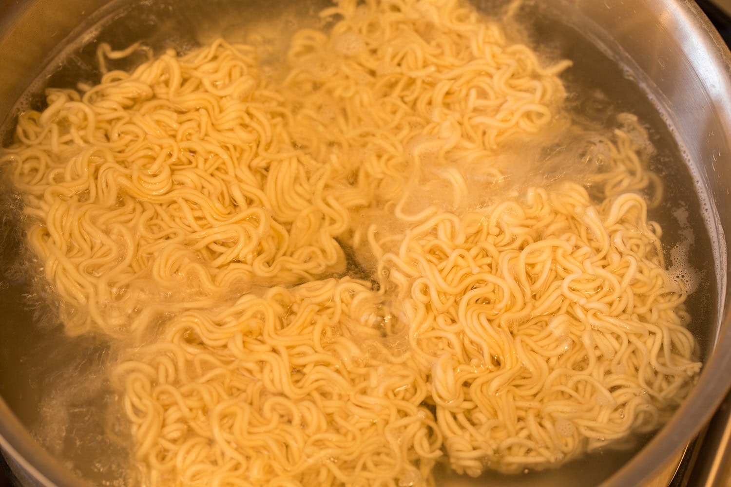 Ramen noodles boiling in a pot of water.