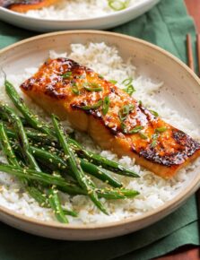 Close up of miso salmon garnished with green onions served over white rice with green beans on the side.