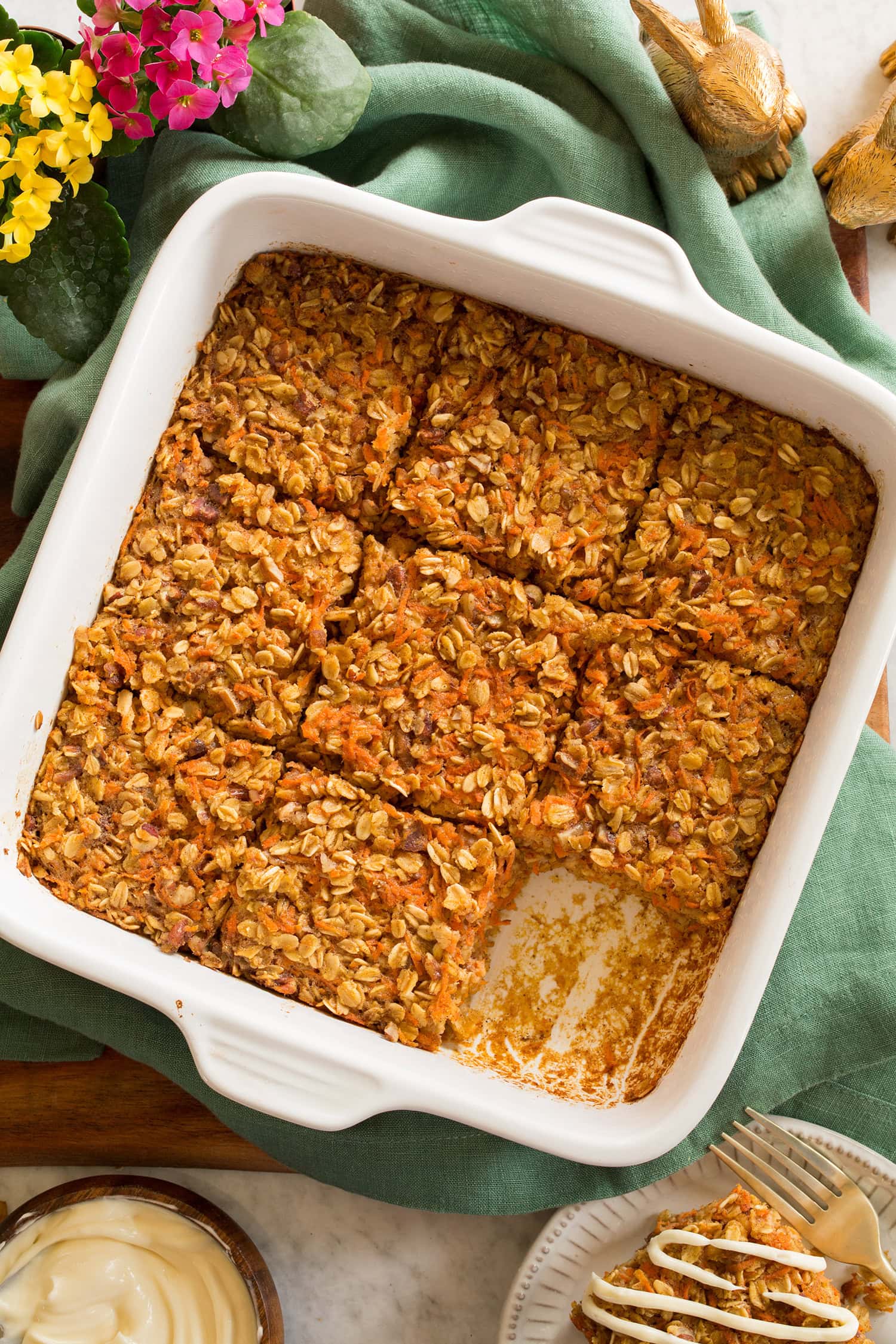 Carrot Cake Baked Oatmeal cut into nine squares in a white ceramic baking dish, shown overhead.