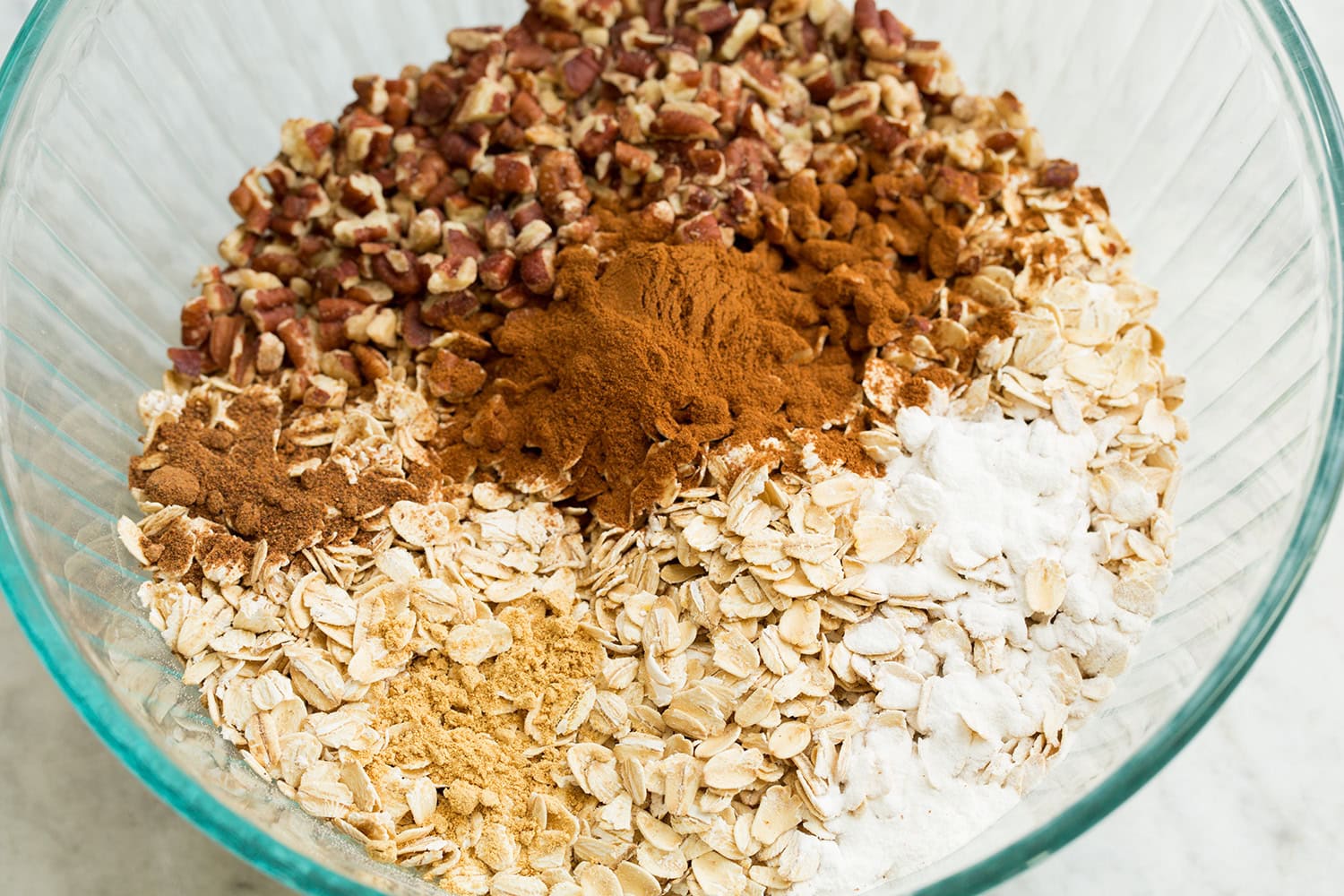 Oats, baking powder, salt, spices and pecans in a mixing bowl.