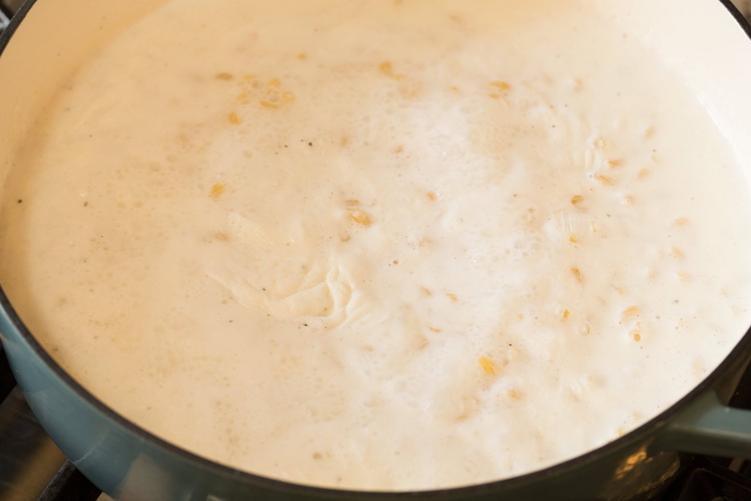 Simmering liquid covering macaroni pasta.