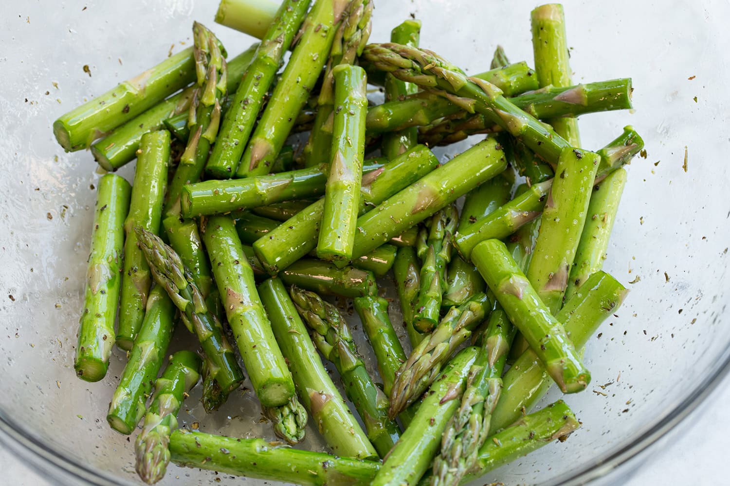 Chopped asparagus with oil in a mixing bowl.