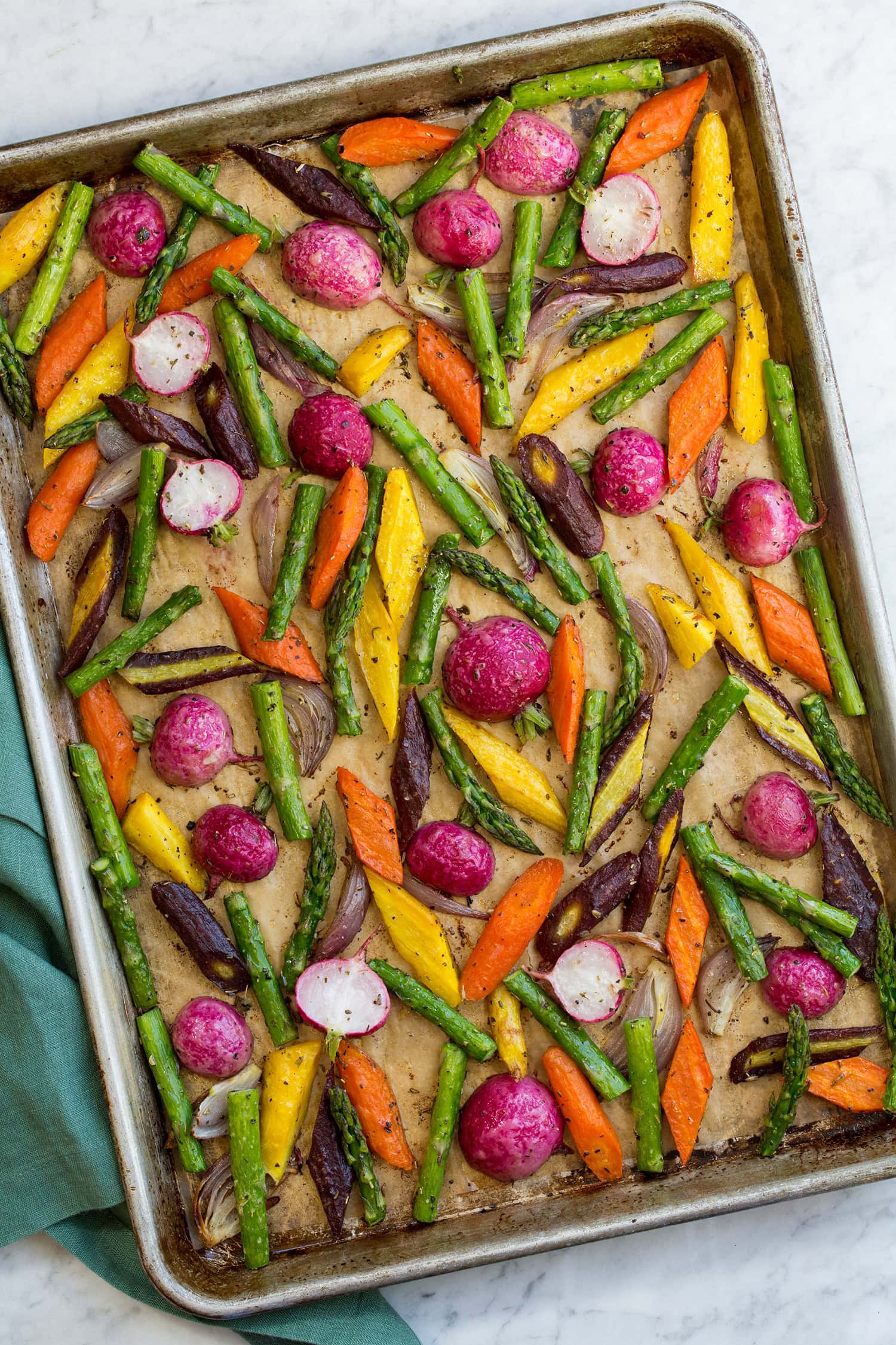 Colorful spring vegetables on a parchment paper lined baking sheet.