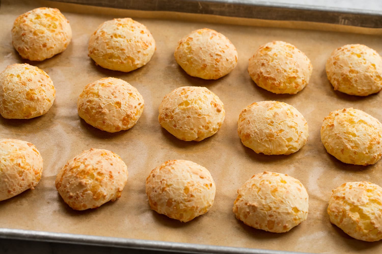 Brazilian Cheese Bread (Pão de Queijo) Completed pao de quiejo bread shown on the baking sheet fully baked.